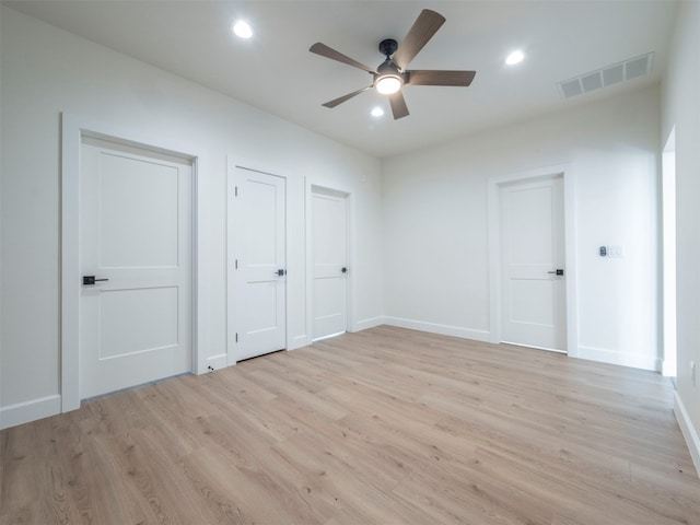 unfurnished bedroom with light hardwood / wood-style flooring, ceiling fan, and multiple closets