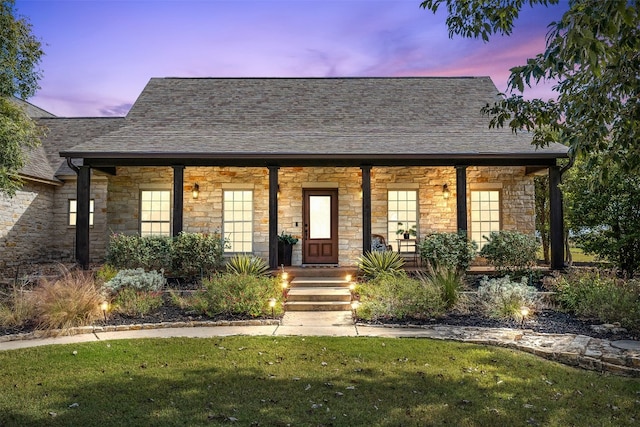 view of front of home with covered porch and a yard