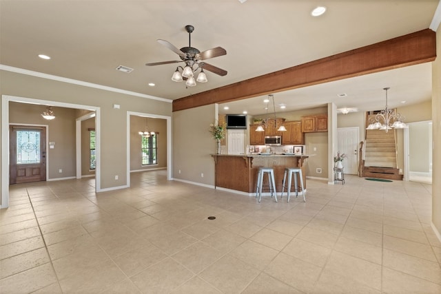 unfurnished living room featuring a wealth of natural light, light tile patterned floors, ceiling fan with notable chandelier, and ornamental molding