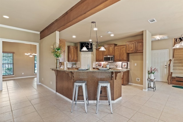 kitchen with light stone countertops, a kitchen bar, kitchen peninsula, and ornamental molding