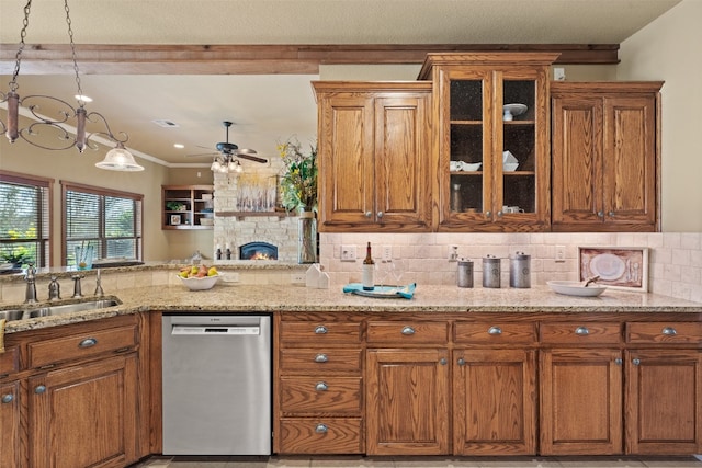 kitchen with backsplash, ceiling fan with notable chandelier, a stone fireplace, stainless steel dishwasher, and light stone counters