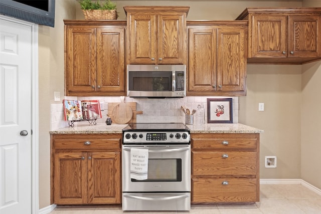 kitchen featuring backsplash, light stone counters, light tile patterned floors, and appliances with stainless steel finishes