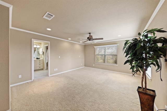 spare room featuring light carpet, a textured ceiling, ceiling fan, and ornamental molding