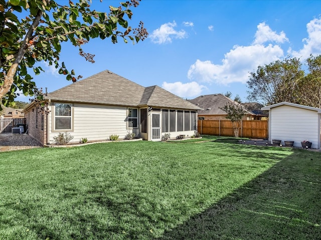 rear view of house with a sunroom, a lawn, and central AC