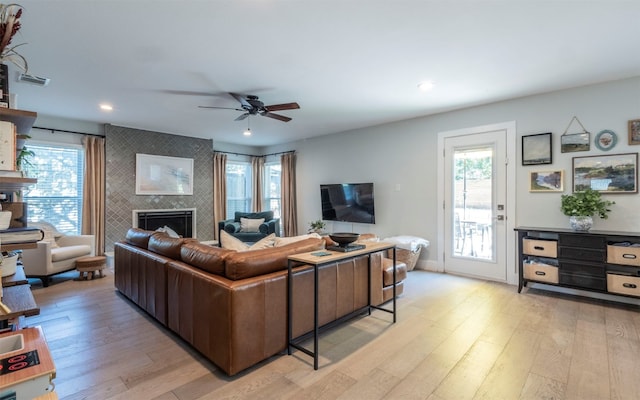 living room with a tile fireplace, light hardwood / wood-style flooring, and plenty of natural light