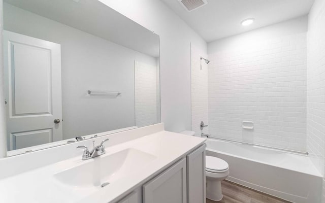 full bathroom with tiled shower / bath combo, toilet, wood-type flooring, and vanity