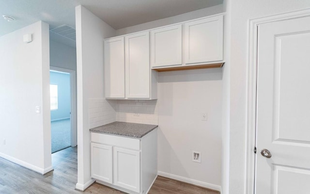 kitchen with tasteful backsplash, white cabinetry, and light hardwood / wood-style flooring