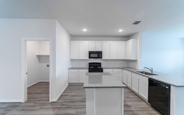 kitchen featuring black appliances, sink, light stone countertops, light hardwood / wood-style floors, and white cabinetry