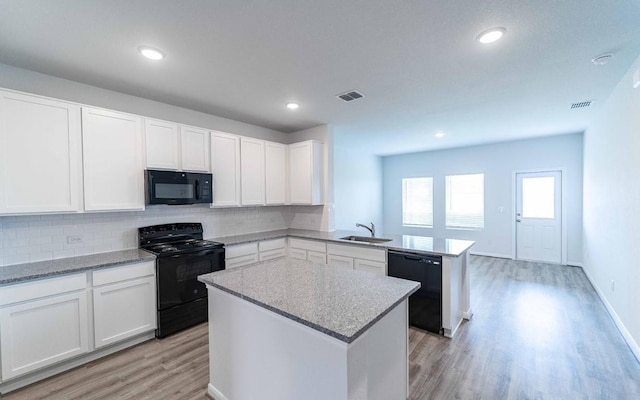 kitchen with white cabinets, a center island, kitchen peninsula, and black appliances