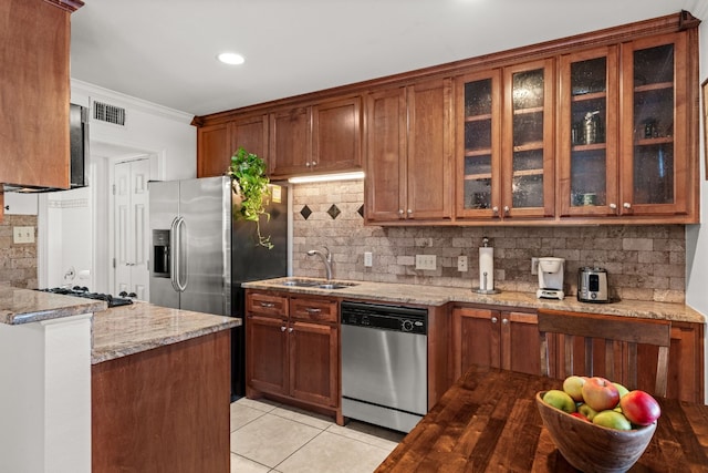 kitchen featuring sink, decorative backsplash, light tile patterned floors, light stone counters, and stainless steel appliances