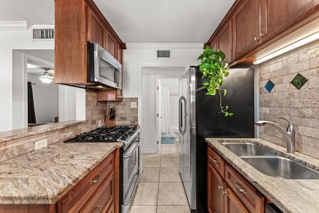 kitchen with light stone countertops, stainless steel appliances, tasteful backsplash, and ornamental molding