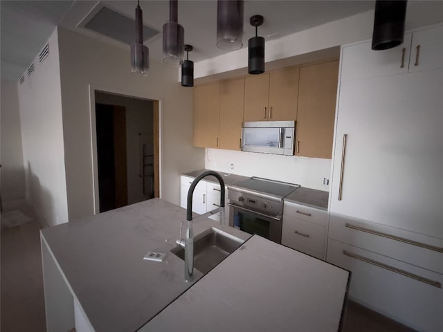 kitchen with hanging light fixtures, cream cabinetry, stainless steel appliances, and sink