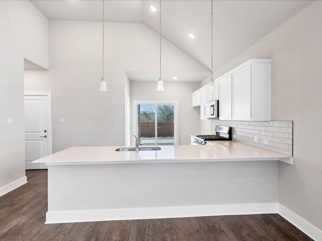 kitchen with kitchen peninsula, stainless steel appliances, sink, high vaulted ceiling, and white cabinets