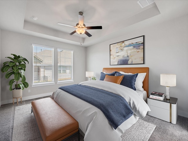 bedroom featuring ceiling fan, carpet floors, and a tray ceiling