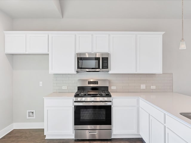 kitchen featuring pendant lighting, dark wood-type flooring, decorative backsplash, white cabinetry, and stainless steel appliances