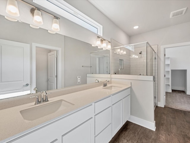 bathroom with vanity, a shower with shower door, and wood-type flooring