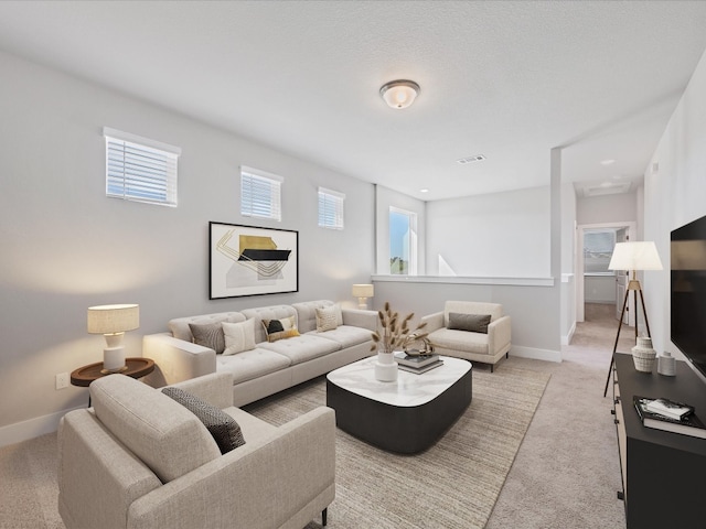 living room with light carpet, a textured ceiling, and a healthy amount of sunlight