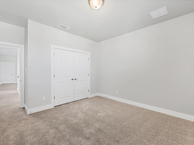 unfurnished bedroom featuring light colored carpet and a closet