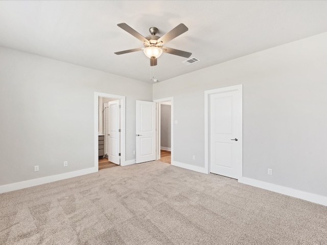 unfurnished bedroom featuring ceiling fan, ensuite bathroom, and light carpet