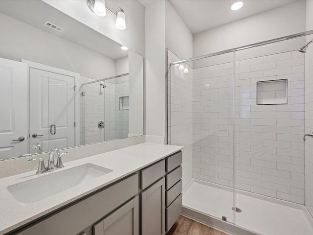 bathroom featuring vanity, a shower with shower door, and wood-type flooring