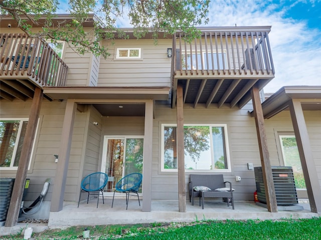 rear view of house with a patio area, a balcony, and central AC unit