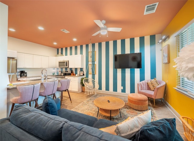 living room featuring light hardwood / wood-style floors, ceiling fan, and sink