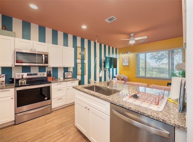 kitchen with light stone countertops, sink, light hardwood / wood-style flooring, white cabinets, and appliances with stainless steel finishes