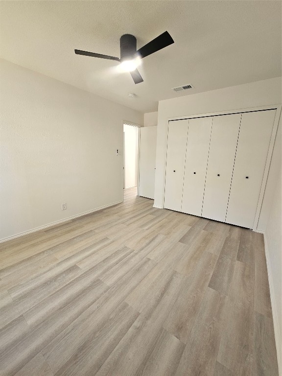 unfurnished bedroom with ceiling fan, a closet, light hardwood / wood-style floors, and a textured ceiling