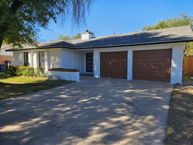 single story home featuring driveway, an attached garage, a chimney, and brick siding