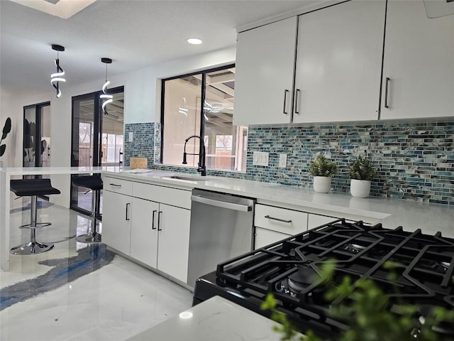 kitchen featuring dishwasher, light countertops, white cabinetry, pendant lighting, and gas stove