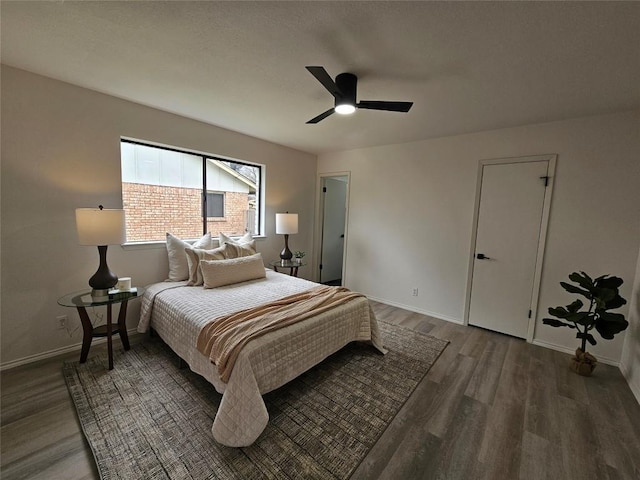 bedroom featuring dark wood-type flooring, a ceiling fan, and baseboards