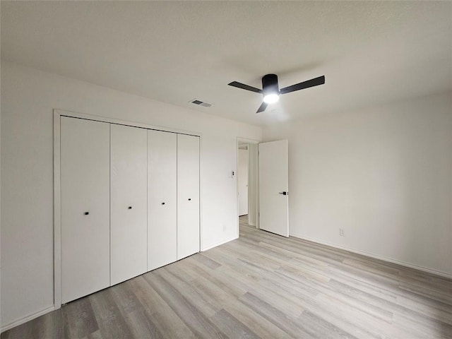 unfurnished bedroom with a closet, visible vents, light wood-style flooring, ceiling fan, and baseboards