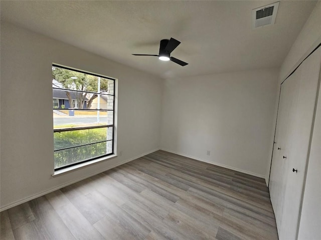 unfurnished bedroom featuring baseboards, a closet, visible vents, and wood finished floors