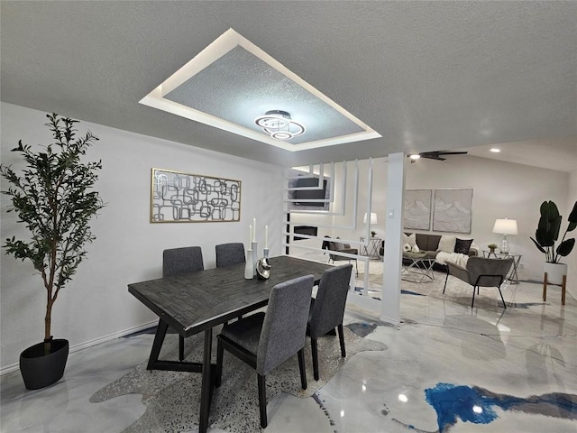 dining area featuring a tray ceiling, a textured ceiling, and baseboards