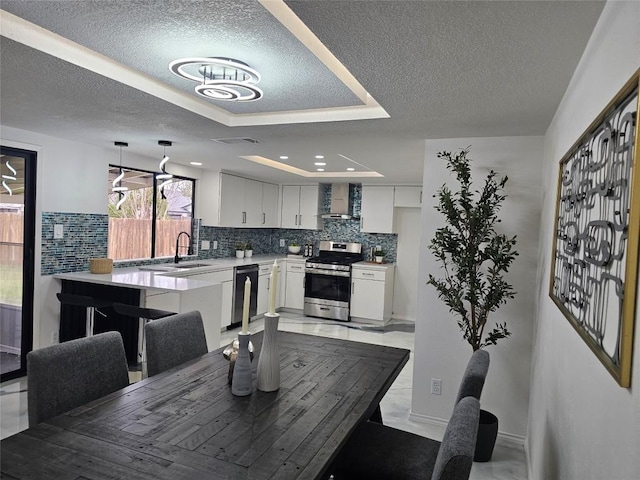 dining area with a tray ceiling, visible vents, and a textured ceiling