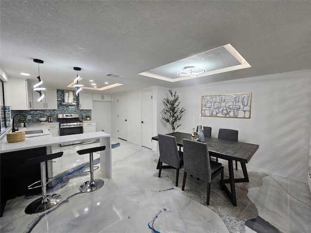 dining space with baseboards, visible vents, a raised ceiling, concrete flooring, and a textured ceiling