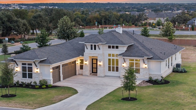 view of front of house featuring a lawn, central AC unit, and a garage