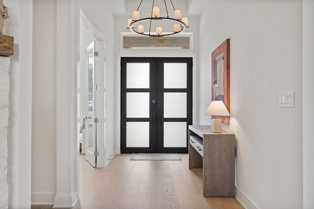 entrance foyer with french doors, an inviting chandelier, and light hardwood / wood-style flooring