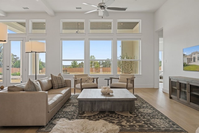 living room featuring dark hardwood / wood-style flooring, beam ceiling, ceiling fan, and a towering ceiling