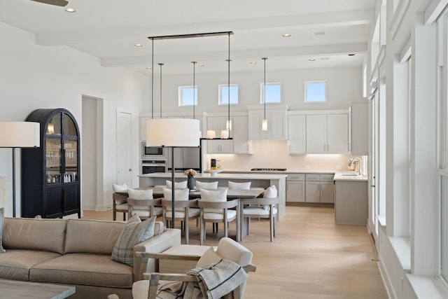 living room featuring a high ceiling, sink, and light wood-type flooring