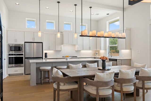 301 Miranda Way, Georgetown, TX 78633 - kitchen featuring stainless steel appliances, a towering ceiling, light wood-style floors, a kitchen island, and light countertops