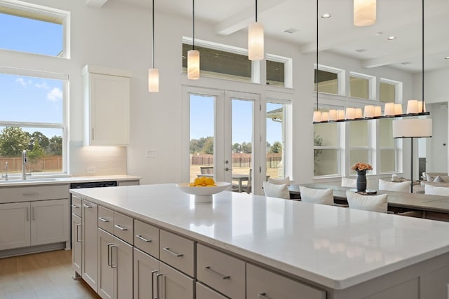 kitchen featuring a kitchen island, decorative light fixtures, tasteful backsplash, sink, and light stone counters