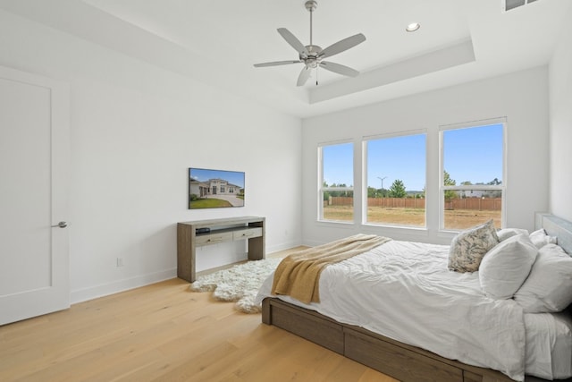 bedroom featuring a raised ceiling, ceiling fan, and light hardwood / wood-style floors