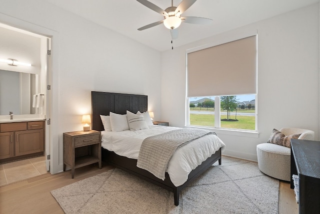 bedroom featuring ceiling fan, light hardwood / wood-style floors, sink, and connected bathroom