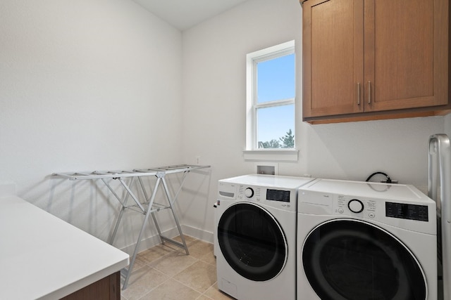 clothes washing area featuring washer and dryer, light tile patterned floors, and cabinets