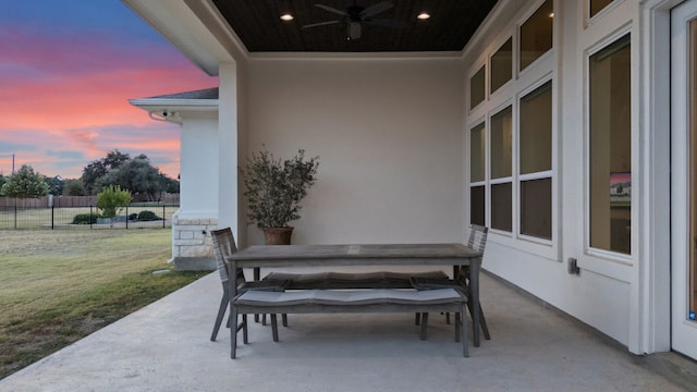 patio terrace at dusk with ceiling fan and a lawn