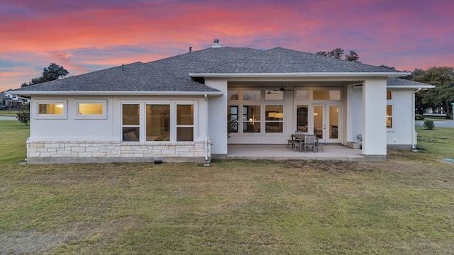 back house at dusk featuring a lawn, a patio area, and ceiling fan