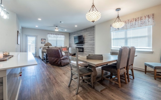 dining space featuring a fireplace, dark hardwood / wood-style flooring, ceiling fan, and a healthy amount of sunlight