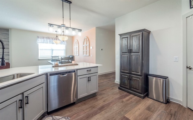 kitchen with sink, hanging light fixtures, dark wood-type flooring, stainless steel dishwasher, and gray cabinets