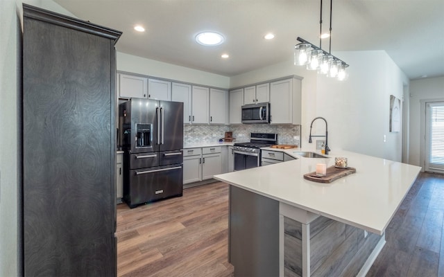 kitchen featuring pendant lighting, sink, a breakfast bar area, wood-type flooring, and stainless steel appliances